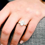 Bague 3 diamants avec pierre principale ovale portée sur l'annulaire d'une femme.