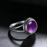 Bague améthyste en argent 925, avec sa pierre cabochon violette et son anneau sculpté.