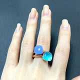 Bague bonbon en cuivre plaqué or rose avec deux cristaux carrés : une bleue opaque et une bleue transparente.