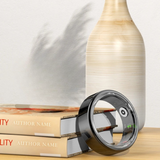 Bague connectée noire intelligente posée sur une table à côté de deux livres.