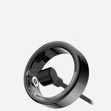 Bague connectée noire avec chargeur magnétique branché pour le recharger.