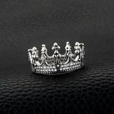 Bague couronne en argent 925 avec des motifs et des cristaux, posée sur un sac en cuir.