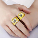 Une main portant 2 bagues en or homme, en or jaune avec une grande pierre de moissanite.