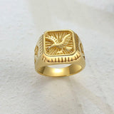 Bague homme pas cher de couleur or, avec un aigle au centre, sur une table blanche.