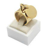 Bague médaille en acier doré avec pendentif cercle, posée sur son écrin blanc.