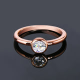 Bague couleur or rose avec une moissanite sertie clos avec son reflet.