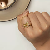 Main de femme portant une bague papillon couleur dorée sur son index.