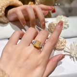 Bague pierre précieuse en argent 925 plaqué platine et zircone carrée jaune, portée sur le majeur d'une femme.