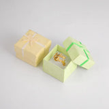 Bague prénom dorée emballée dans une petite boîte cadeau de couleur vert pâle.