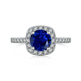Bague saphir en argent sterling 925 avec une zircone bleue taille ronde entourée d'un halo de petites pierres.