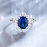 Bague saphir bleue avec des pierres blanches disposées comme des pétales.
