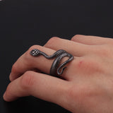 Main portant une bague serpent de couleur noire, s'enroulant autour de son doigt.