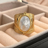 Bague bohème avec un anneau réglable en acier doré et une pierre ovale blanche.