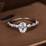 Bagues de fiançailles avec une pierre principale ovale, flanquée de petites pierres ovales sur l'anneau.