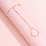 Bracelet bague en cuivre de couleur doré, avec la bague et le bracelet reliés par une chaîne.