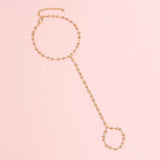 Bracelet bague de couleur dorée avec des chaînes et de petites boules.