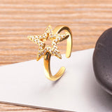 Bague en cuivre doré à taille réglable avec une grosse étoile et de petits diamants.