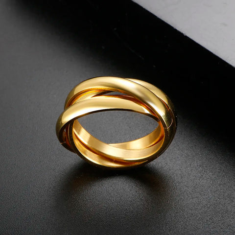 Bague 3 anneaux dorée, posée sur une surface noire pour mettre en valeur son éclat.