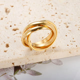 Une bague 3 anneaux dorée, posée sur une petite surface texturée.