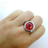 Main de femme portant une bague Akatsuki rouge avec un kanji noir.