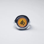 Bague Akatsuki avec l'anneau de couleur argent et une pierre jaune avec un kanji noir.