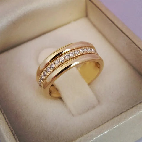 Bague alliance dorée ornée d'une rangée de zircones cubiques, présentée dans un écrin.