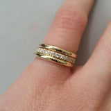 Main de femme portant une bague alliance dorée ornée d'une rangée de zircones cubiques.