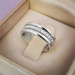 Bague alliance argentée ornée d'une rangée de zircones cubiques présentée dans un écrin beige.