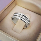 Bague alliance argentée ornée d'une rangée de zircones cubiques présentée dans un écrin beige.