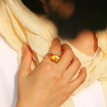 Main de femme portant une bague ambre en argent sur son majeur.