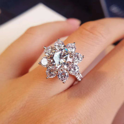 Main portant une magnifique bague argent femme originale en forme de fleur, avec une moissanite centrale ronde et des pétales en pierre.