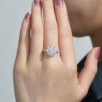 Main portant une bague argent femme originale en forme de fleur, avec une moissanite ronde et des pétales en pierre.