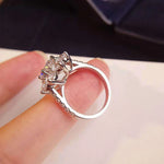 Vue latérale d'une bague argent femme originale avec sa monture à fleur et ses pierres précieuses sur l'anneau.