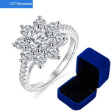 Bague argent femme originale avec une moissanite 1 carat et de pierres formant des pétales, à côté de sa boîte bleue.