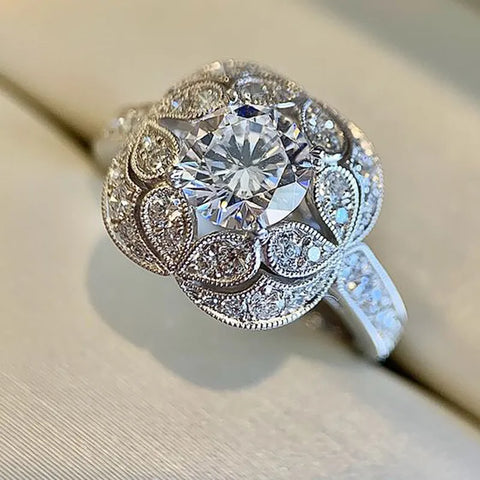 Bague art déco avec une pierre centrale en zircone cubique entourée d'un motif floral pavé de petites pierres.