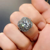 Main de femme portant une bague art déco avec une grande pierre centrale en zircone et un motif floral.