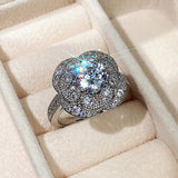 Bague art déco avec une pierre centrale en zircone cubique et un design floral, présentée dans un écrin de velours.