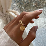 Main de femme portant une bague avec pendentif de couleur or.