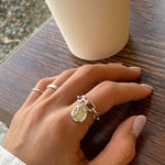 Main de femme portant une bague avec pendentif de couleur argent.