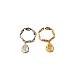 Bague avec pendentif de couleur or et de couleur argent sur un fond blanc.