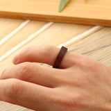 Bague bois marron portée sur l'auriculaire d'un homme.