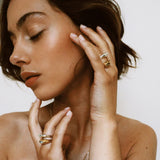 4 bagues cabochons en acier portées sur les annulaires d'une femme, deux argentées, et deux dorées.