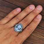 Main d'homme portant la bague camée bleue.