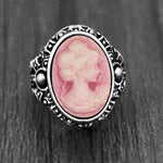 Bague camée avec un anneau argenté à motifs et une pierre ovale rose.