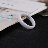 Bague céramique blanche posée sur le bord d'un livre ouvert.