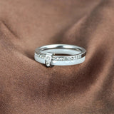 Bague céramique blanche posée sur un tissu marron brillant.