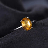 Bague citrine en argent 925 avec une citrine jaune ovale posé sur un tissu noir.