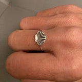 Bague coquillage couleur doré portée sur le majeur d'une femme