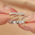 Une paire de mains tenant deux bagues mariage femme. L'une orné d'une double rangée de pierres et l'autre avec une unique pierre sertie. 