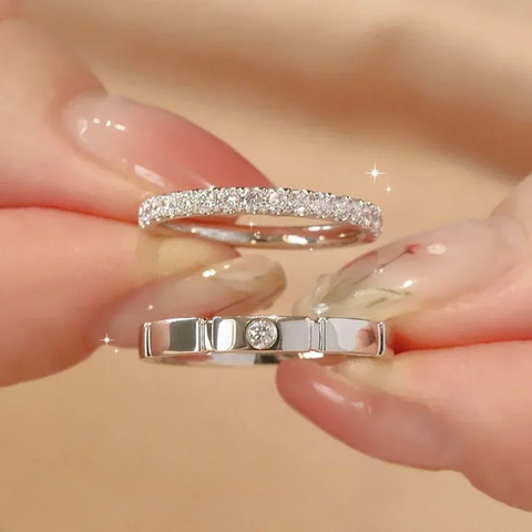 Une paire de mains tenant deux bagues mariage femme. L'une orné d'une double rangée de pierres et l'autre avec une unique pierre sertie. 